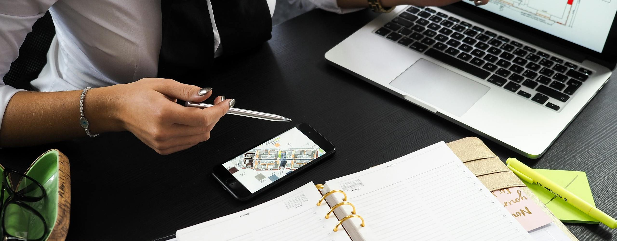A business professional working on real estate project plans using multiple devices in an office setting.