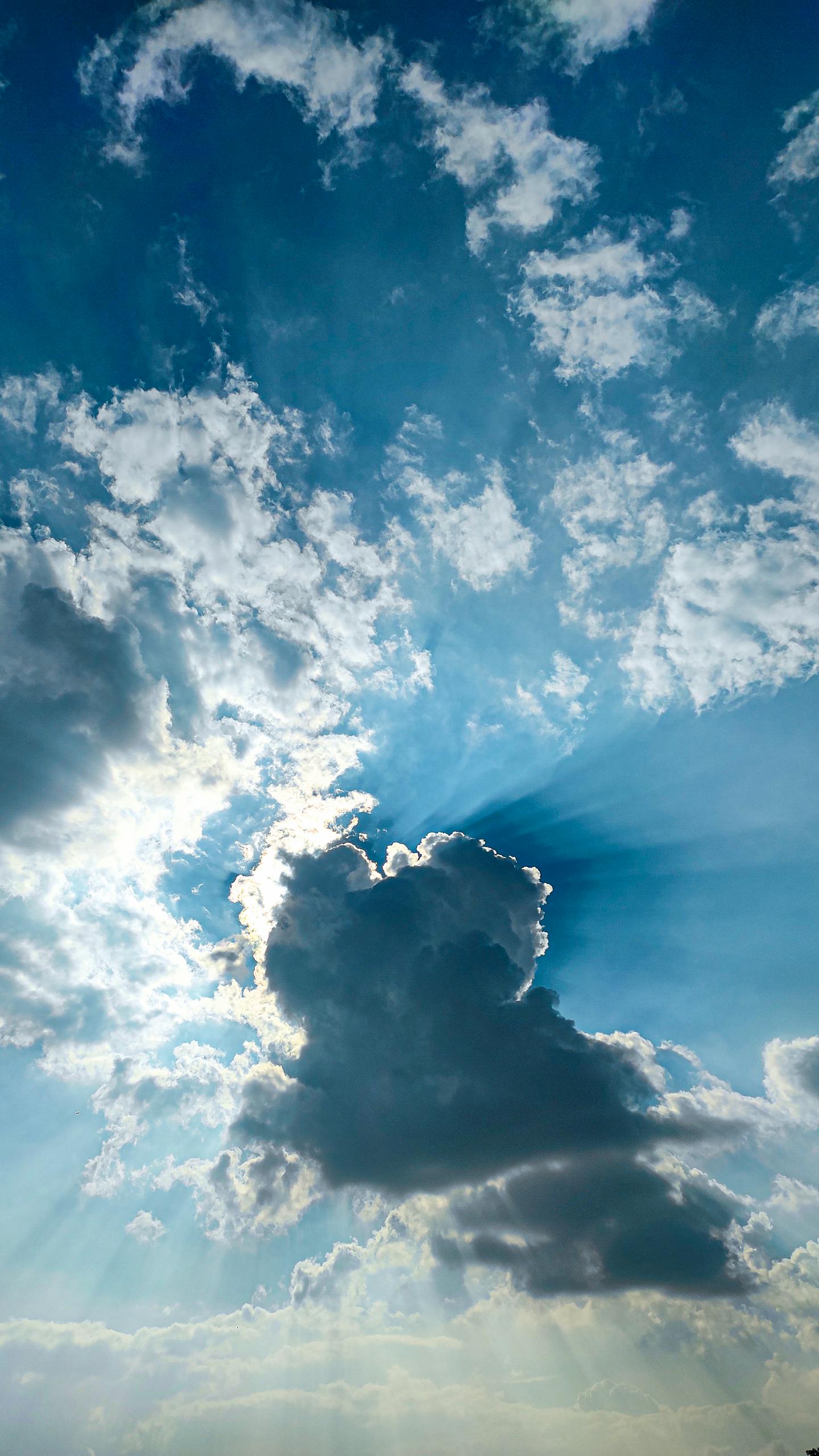 Beautiful view of sunbeams shining through clouds in a blue sky over Bengaluru, India.