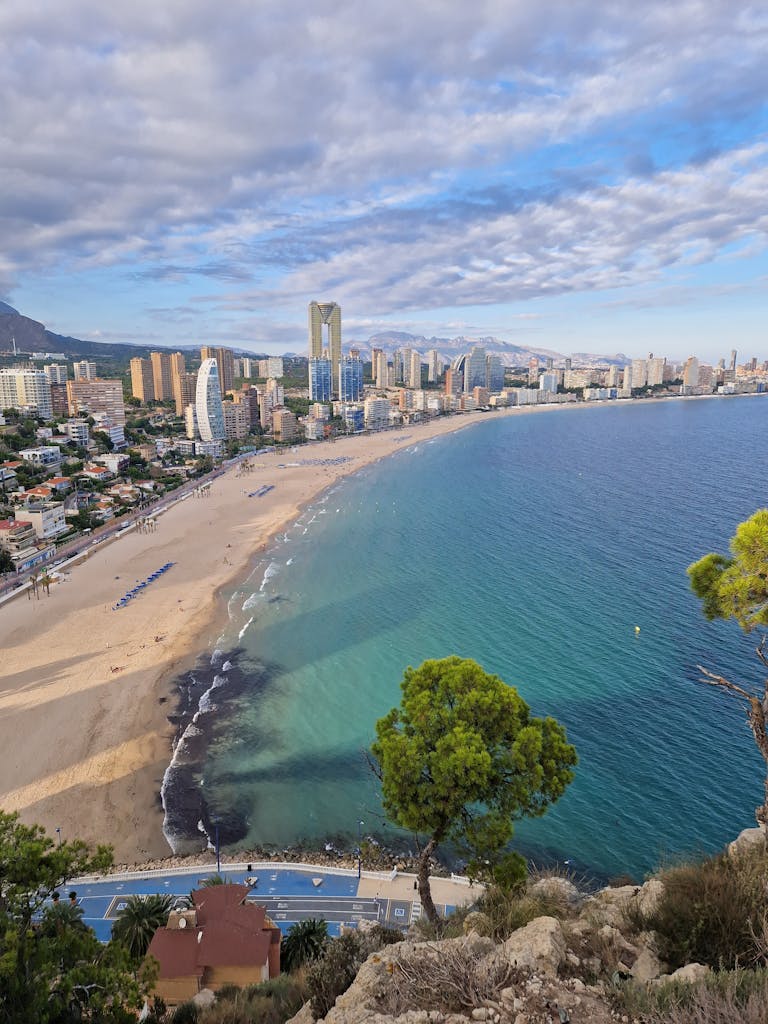 Stunning aerial view of Benidorm's beachfront skyline with clear blue sea and sandy shores.