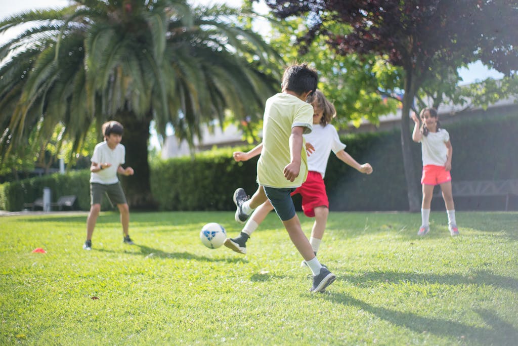 Group of kids enjoying a game of soccer on a grassy field in Portugal.