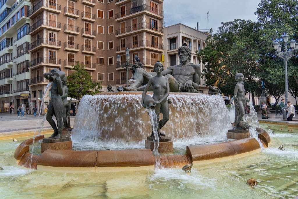 The iconic Turia Fountain in Valencia's Plaza del Ayuntamiento, capturing classical sculptures and vibrant city life.